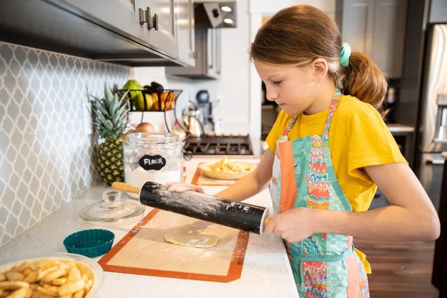 A young girl rolling out dough during a kids cooking session